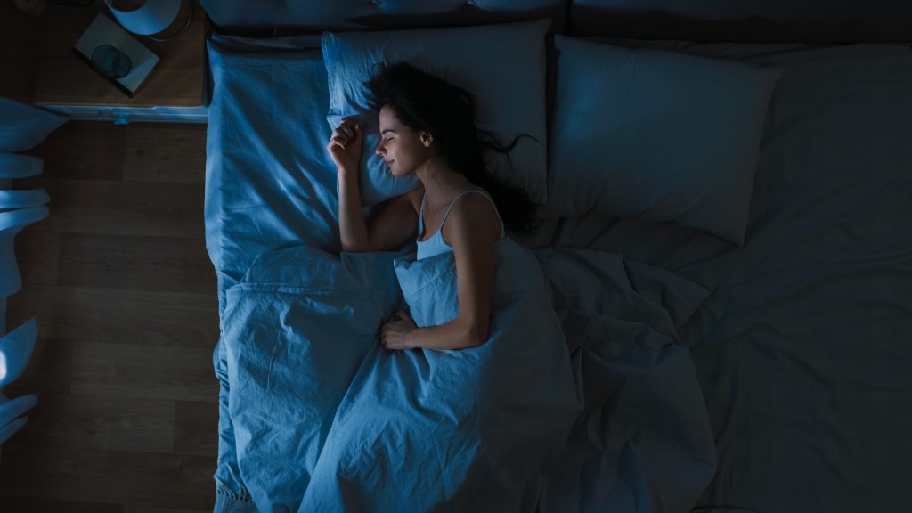 zdjęcie przestawia śpiącą kobietę, która uśmiecha się przez sen; odpowiednia ilość przespanych godzin ma wpływ na mniejsze ryzyko wystąpienia depresji 