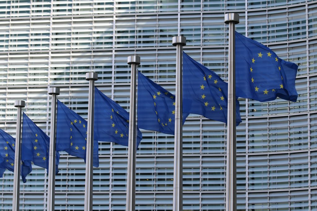 zdjęcie przedstawia flagi unii europejskiej zawieszone być może przed budynkiem komisji europejskiej