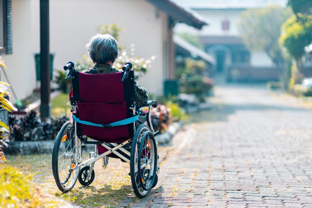 zdjęcie przedstawia starszą osobę na wózku