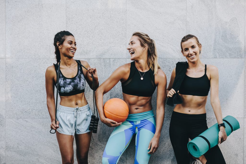 zdjęcie: trzy kobiety w sportowych strojach, śmieją się; ich sylwetki sugerują, że dbają o właściwy deficyt kaloryczny