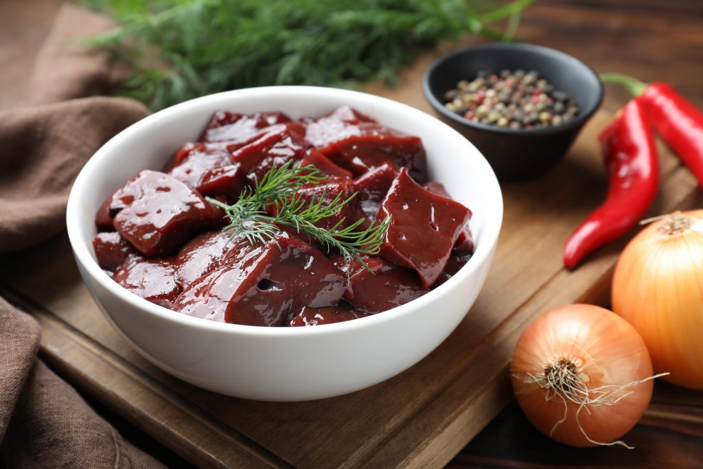 zdjęcie przedstawia surowe, czerwone mięso, źródło żelaza, w białej misce