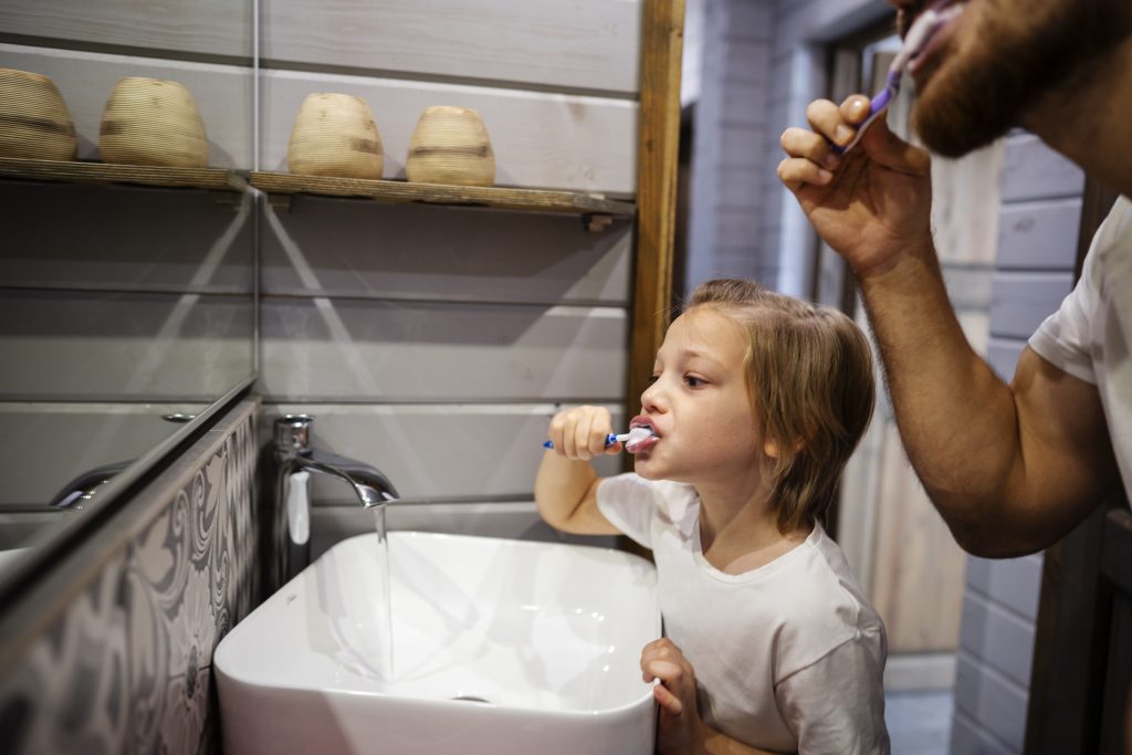 zdjęcie: dorosły mężczyzna i chłopiec myją zęby przed lustrem w łazience