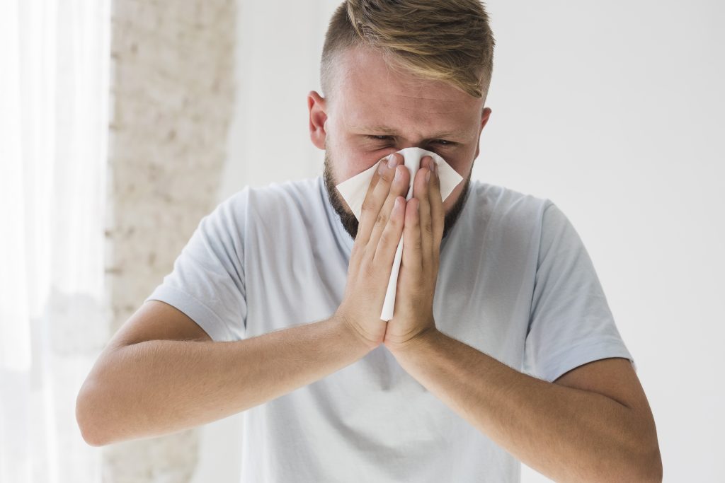 zdjęcie: młody mężczyzna wydmuchujący nos. być może ma alergię na pyłki roślin