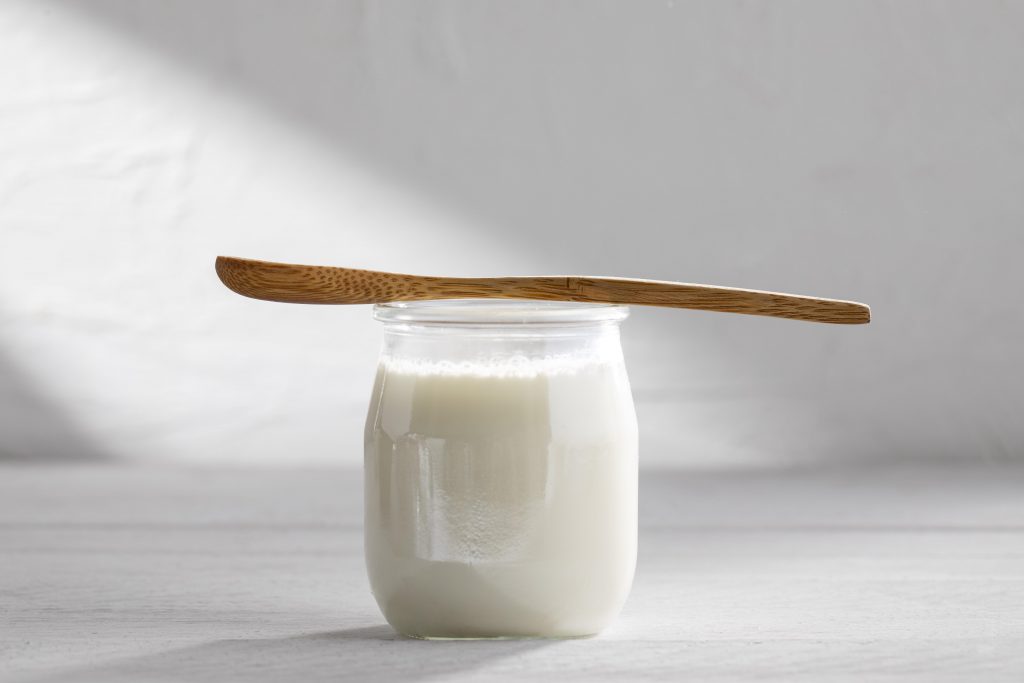 zdjęcie przedstawia jogurt naturalny w szklanym słoiczku, produkty ten jest naturalnym prebiotykiem