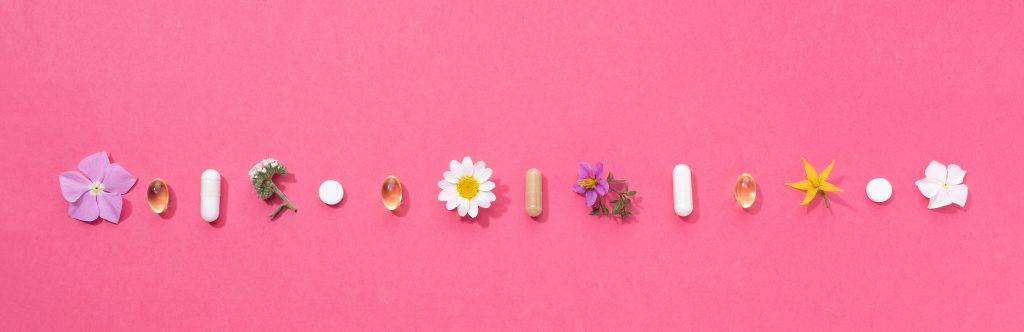 Vitamin capsules and dietary supplements isolated on pink background. Panoramic format.